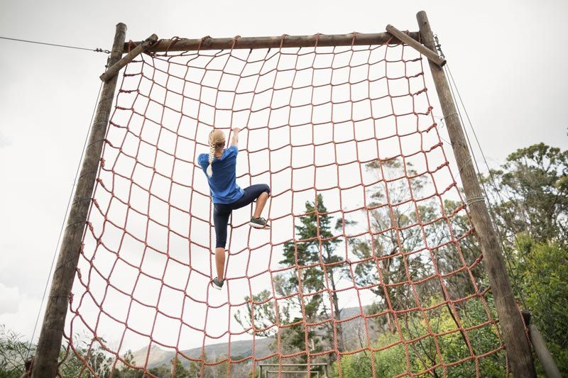 Image of woman climbing obstacle on ropes course